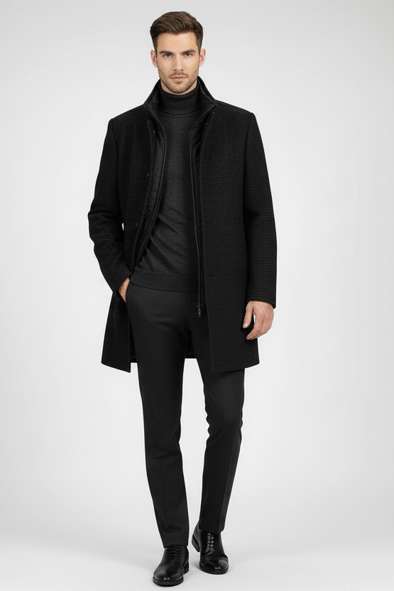 Man wearing a stylish coat houndstooth windvanger zwart-grijs over a black turtleneck and trousers.