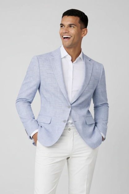 Colbert miniruit lichtblauw worn by a smiling man in a stylish outfit with white trousers.