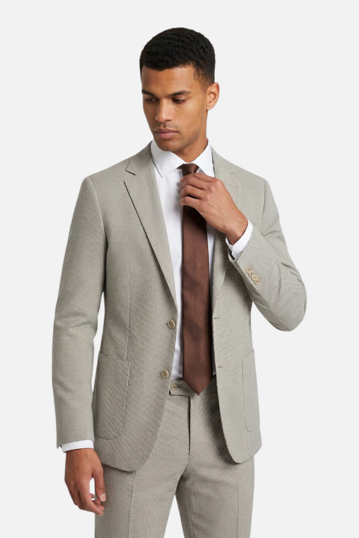 Homme portant un colbert pied-de-poule beige avec cravate marron.