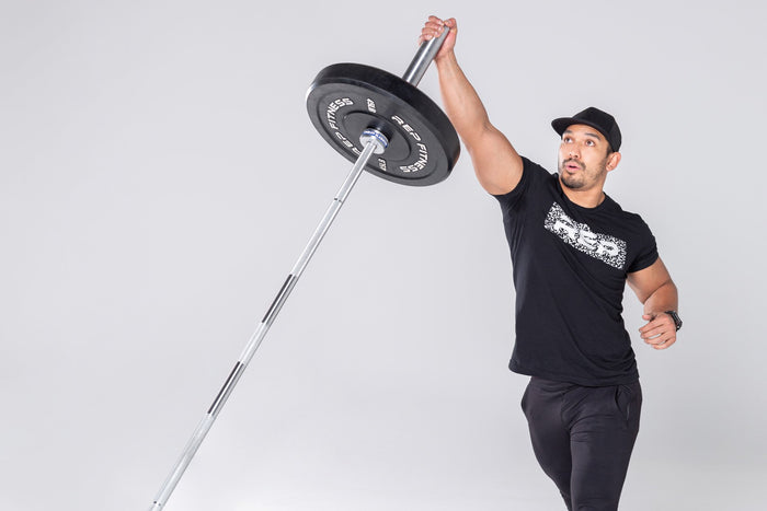 Lifter performing a single-arm overhead press with a loaded barbell in the REP Free Standing Landmine.