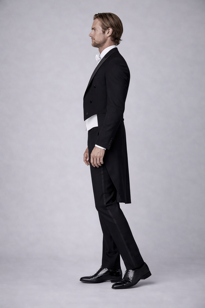 Elegantly dressed man in a formal Rokkostuum compleet, suitable for events with strict dress codes.