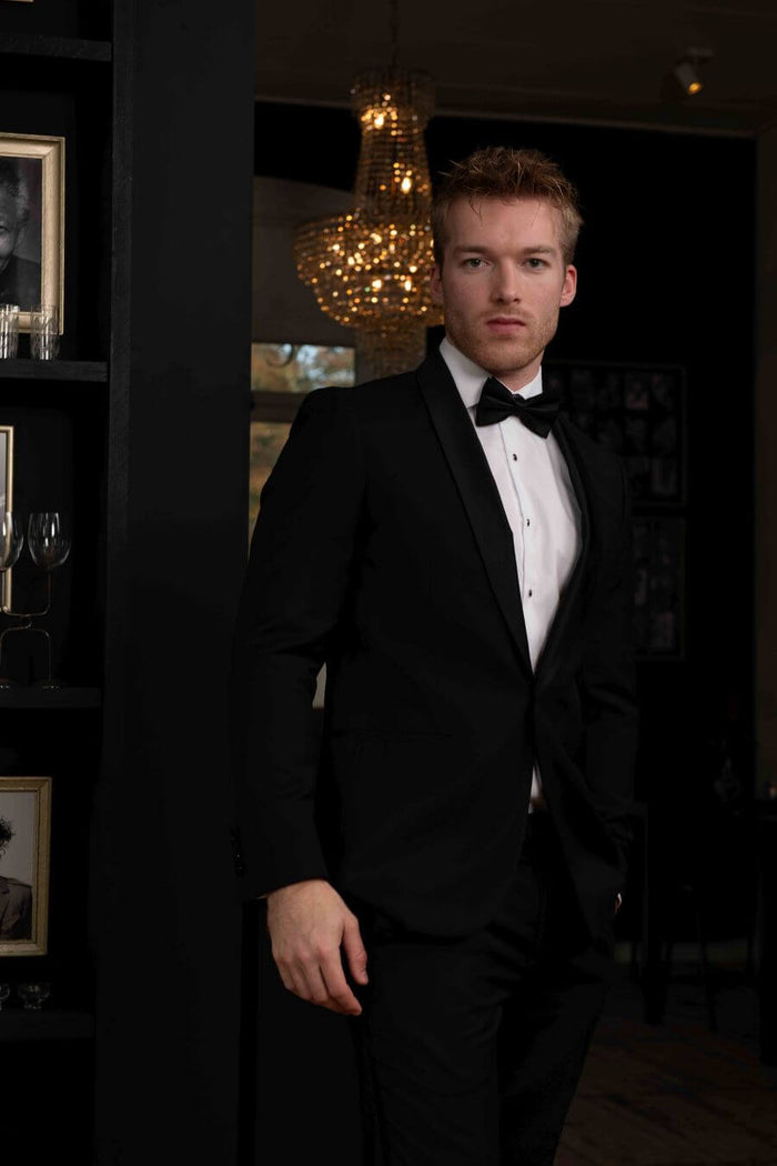 Modern gentleman in a smoking compleet, featuring a tuxedo and bow tie, ready for formal events.